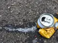 Zgnieciona puszka po piance montażowej leży na asfalcie, obok śladów piany. Pamiętaj o prawidłowej utylizacji!
