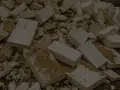 Stos białych, połamanych kawałków styropianu z widocznymi śladami ziemi.