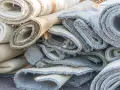 Stare, zrolowane dywany czekają na utylizację. Zastanawiasz się, gdzie wyrzucić dywan? Ta sterta to dowód, że czasem trzeba się ich pozbyć.