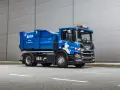 Niebieska śmieciarka Scania z napisem "ODPADY" i logo BYS. Pojazd gotowy do odbioru gruzu, z kodem odpadu na tablicy.