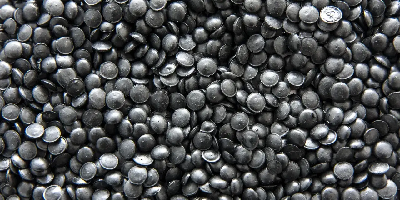 Mnóstwo czarnych granulek regranulatu HDPE, gotowych do przetworzenia w nowe produkty.