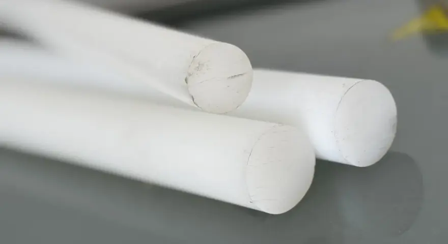 Trzy białe, okrągłe pręty, przypominające kredę tarnamid, leżą na szarej powierzchni.