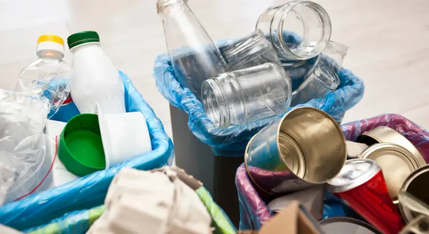 Segregacja odpadów: szklane słoiki, plastikowe butelki i puszki czekają na wywóz śmieci.