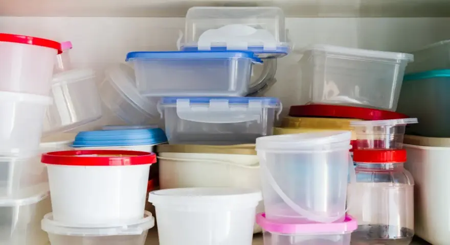 Stos pojemników na żywność, niektóre z kolorowymi pokrywkami. Uważaj na ftalany w plastiku.