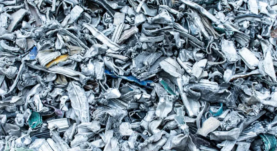 Góra poskręcanego, poszarpanego złomu metalowego, gotowego do recyklingu metalu. Widać fragmenty niebieskiego i żółtego plastiku.