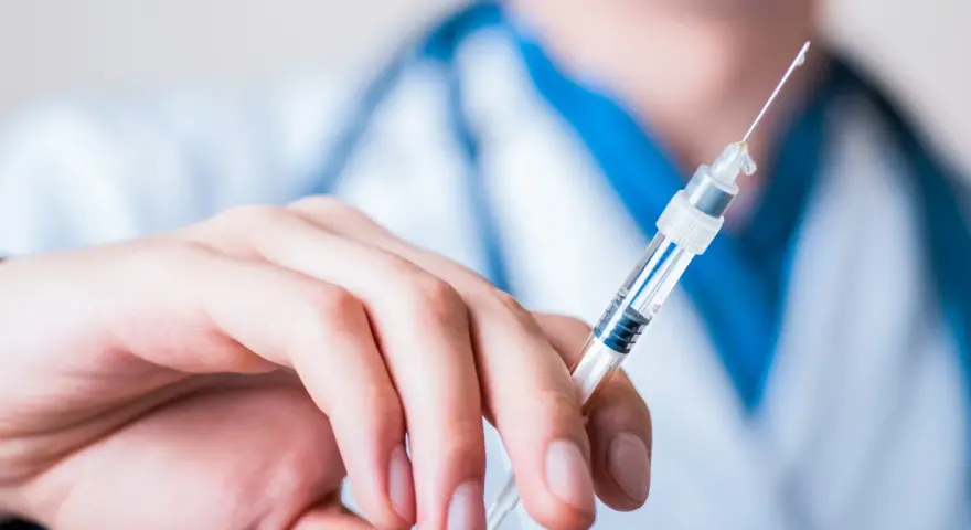 Dłoń trzymająca strzykawkę z heparyną. Pytanie: gdzie wyrzucić strzykawki po heparynie? Bezpieczne utylizowanie jest kluczowe.
