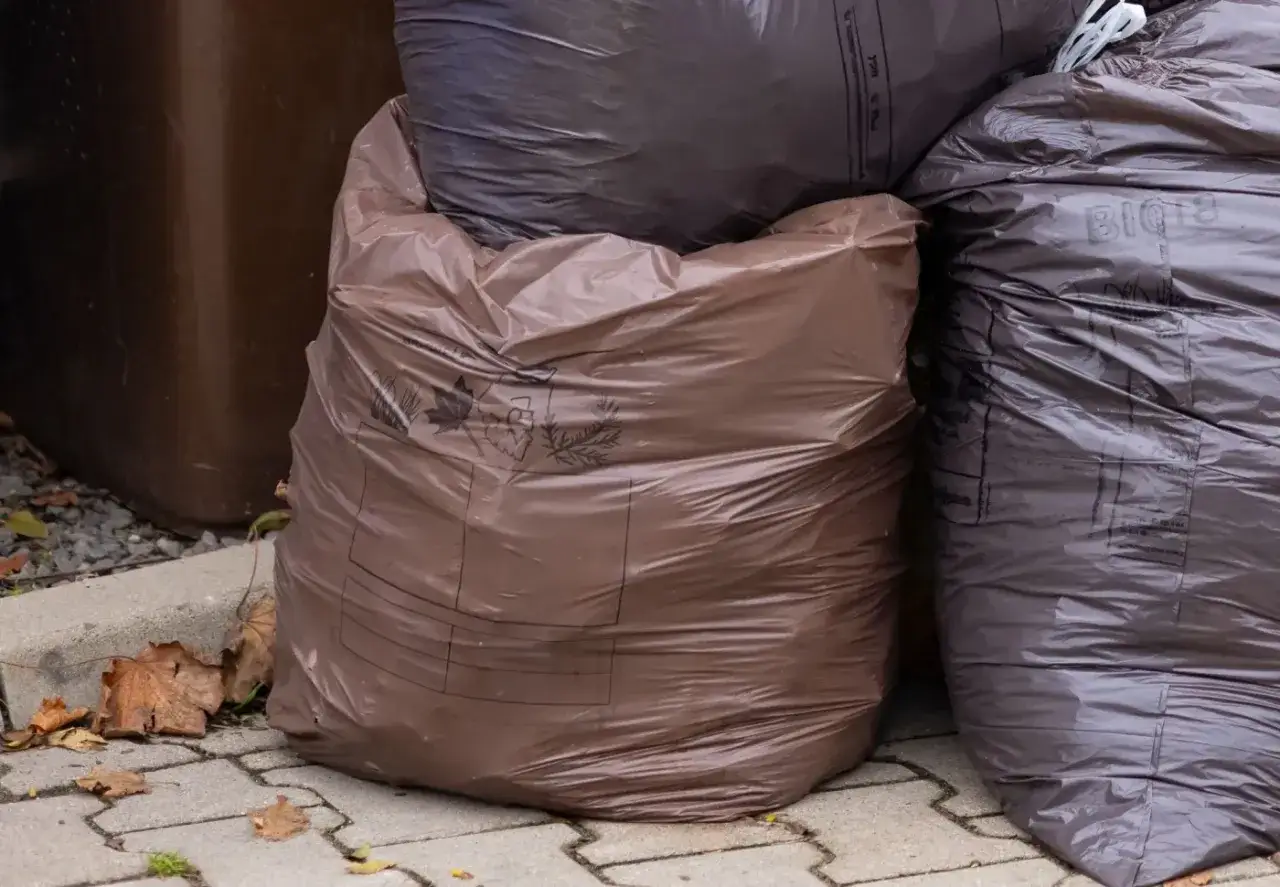 Brązowe i ciemne worki na śmieci, jeden z nich z napisem 